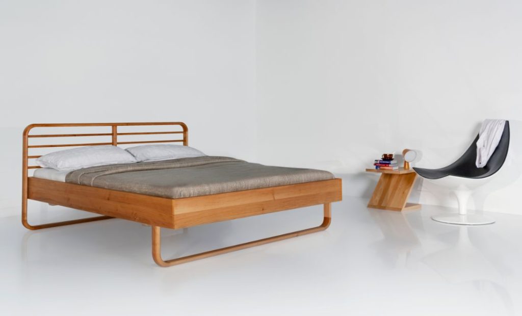 Massiholzbett Lukas von Luna mit passendem Nachttisch und Cocktailsessel.