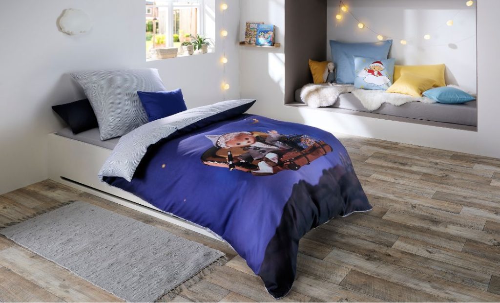 Sandmännchen auf Reisen im fliegenden Koffer auf Kinderbettwäsche.